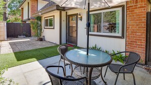 A patio with a glass table and wicker chairs, a brick wall, and a door. - Pet-friendly Houston Vacation Rental w/ Patio! (Houston)