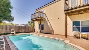 A swimming pool with a wooden deck, a covered patio, and a fenced backyard. - South Padre Island Condo w/ Shared Outdoor Pool! (South Padre Island)