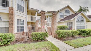 A multi-story residential building with a brick facade, multiple balconies, and a well-maintained lawn. - 6 Mi to Disney: Family-friendly Condo in Kissimmee (Kissimmee)
