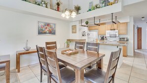 A dining area with a wooden table and chairs, a kitchen with wooden cabinets, and a ceiling light fixture. - 6 Mi to Disney: Family-friendly Condo in Kissimmee (Kissimmee)