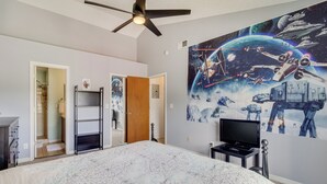 A bedroom with a large bed, a ceiling fan, a TV, and a space-themed wall mural. - 6 Mi to Disney: Family-friendly Condo in Kissimmee (Kissimmee)