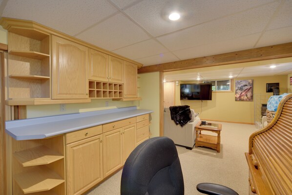 A room with wooden cabinets, a blue countertop, a bed, and a television. - Hermantown Home w/ Decks, Grill & Hot Tub! (Duluth)