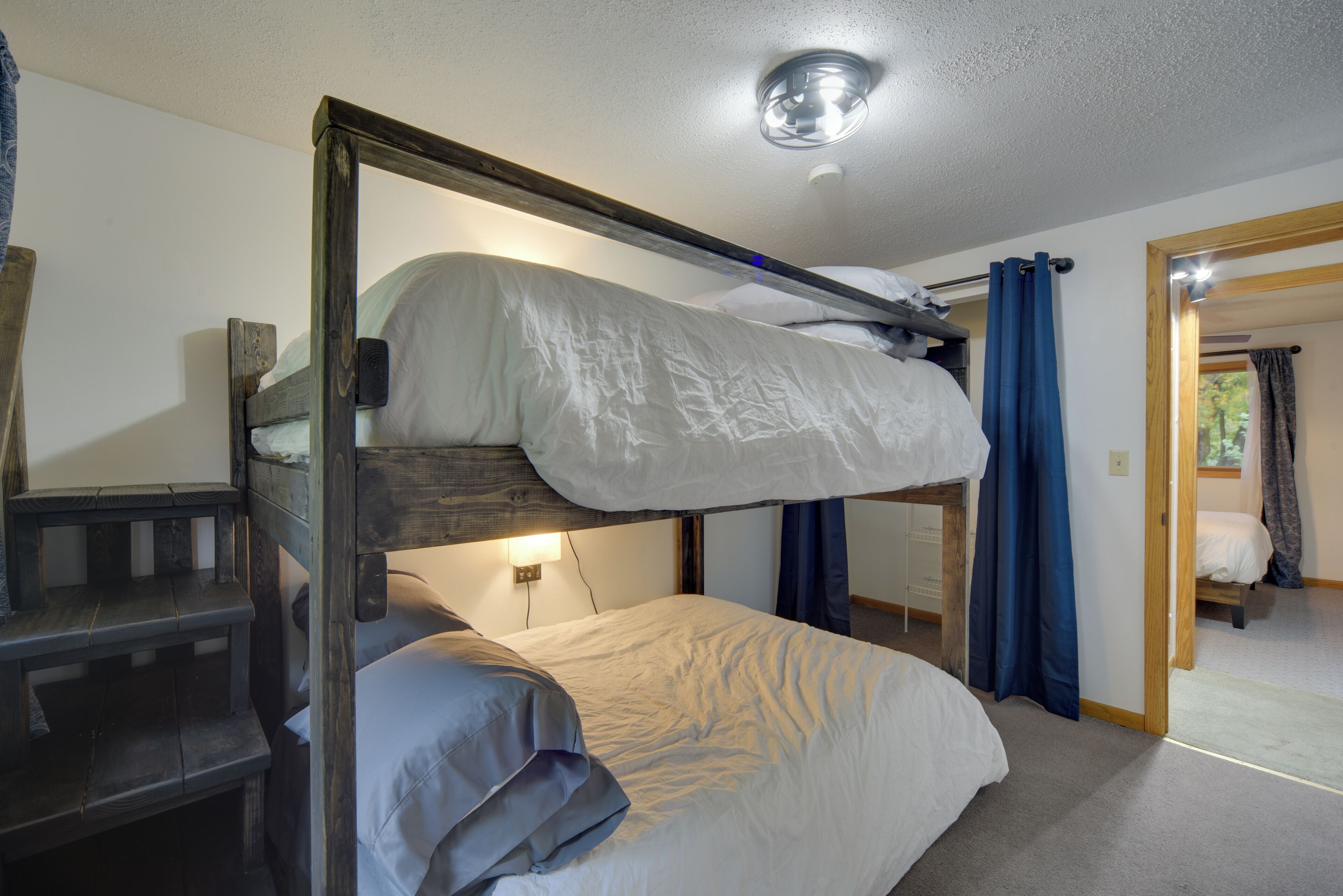 A bunk bed room with a wooden frame, a desk, and a mirror.