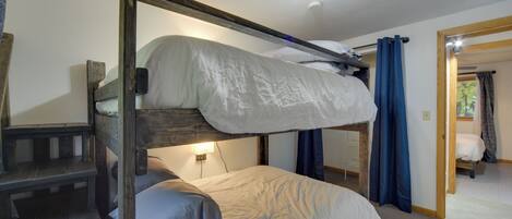 A bunk bed room with a wooden frame, a desk, and a mirror.