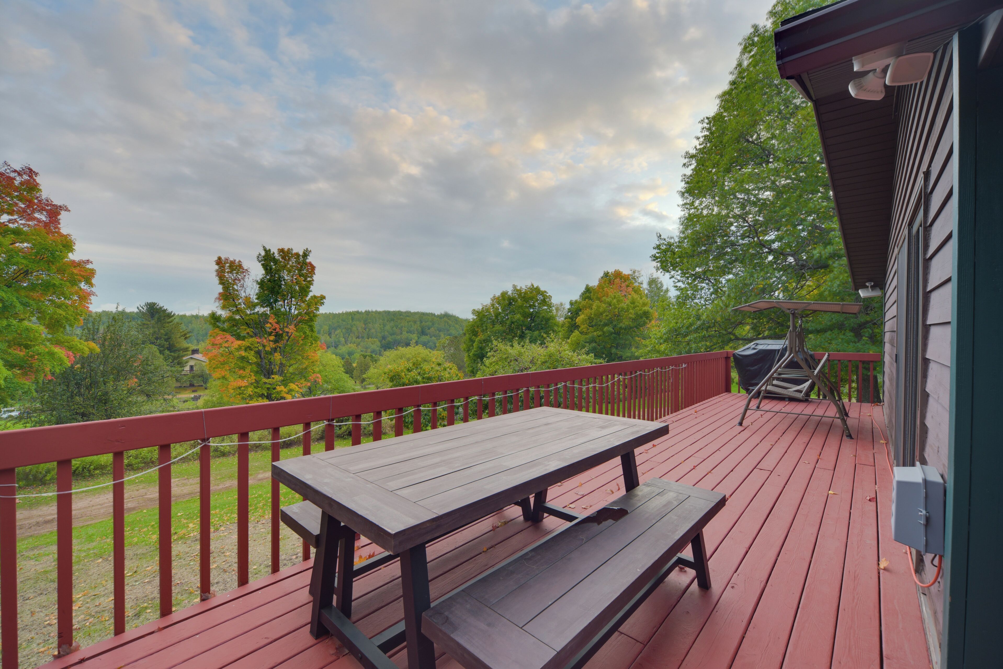 A wooden deck with a picnic table and a barbecue grill.