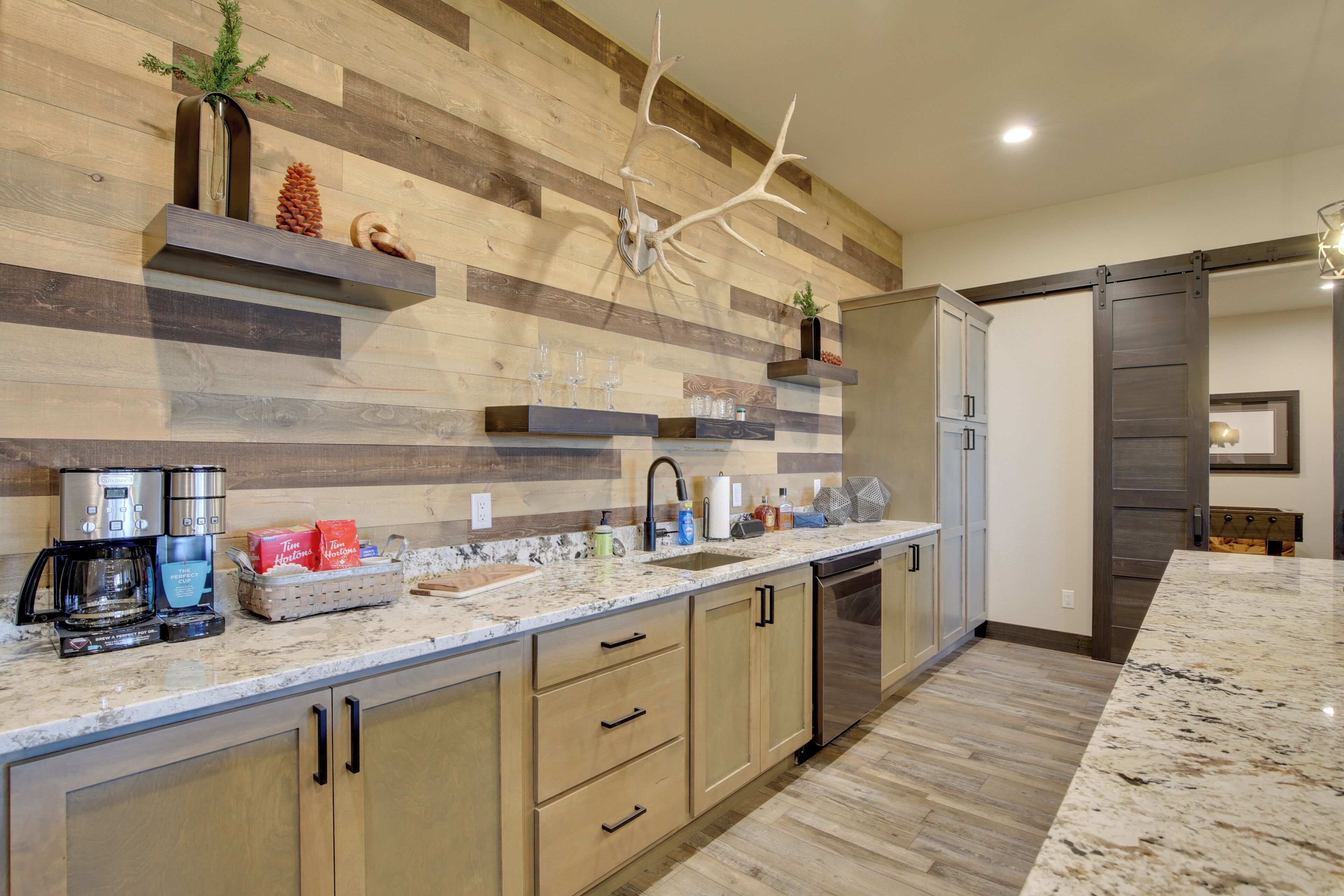 A modern kitchen with wooden paneling, a large island with a sink, and built-in appliances.