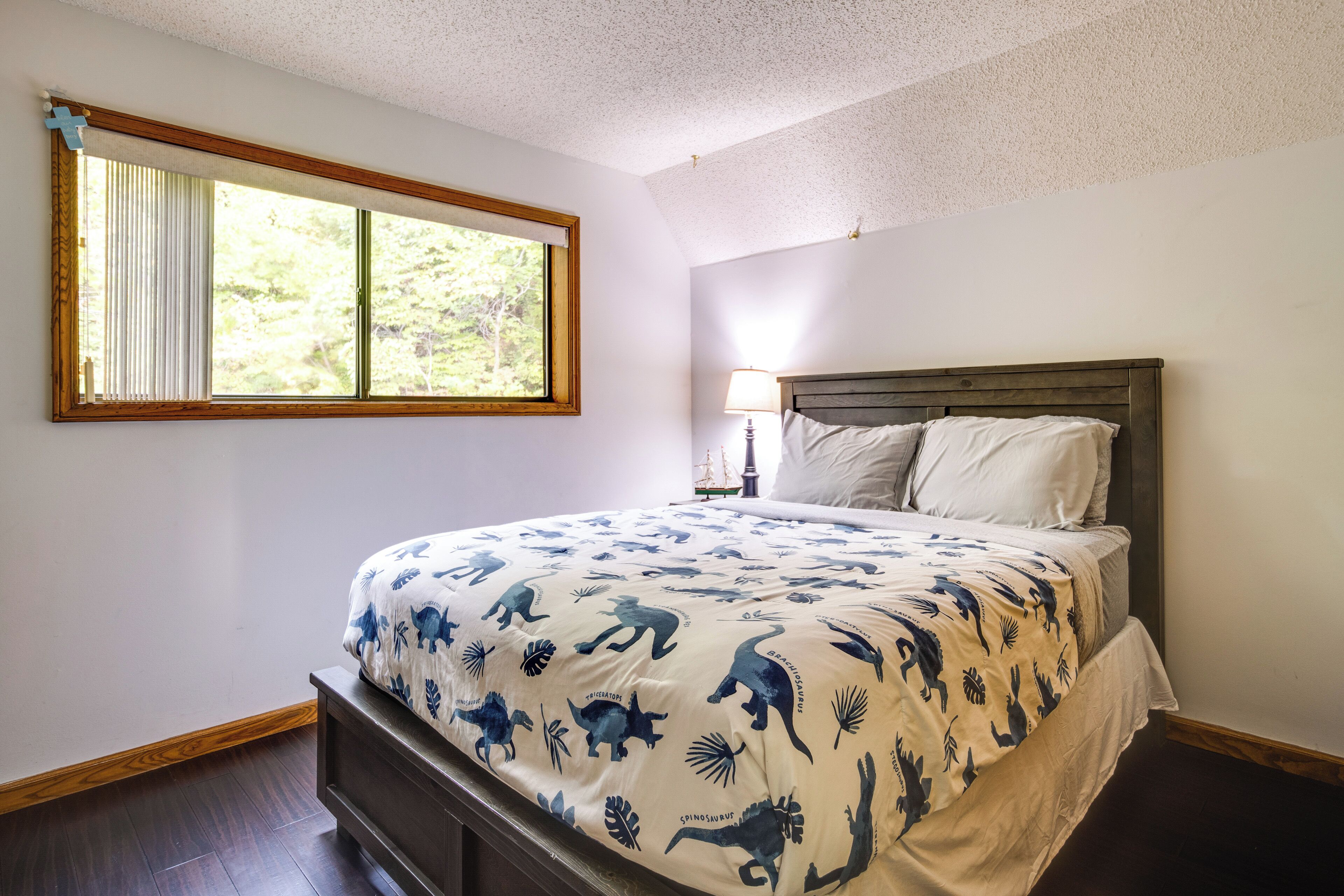 Une chambre à coucher avec un lit, une fenêtre et une table de chevet avec une lampe.