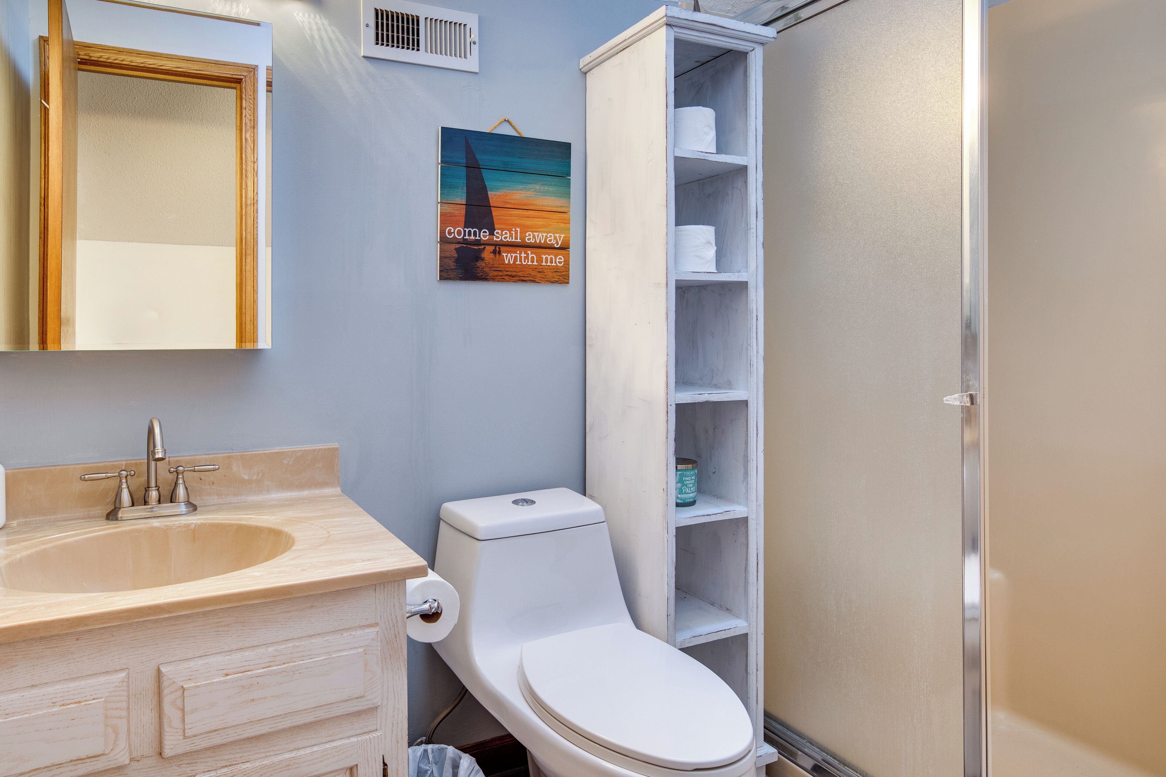 A bathroom with a sink, toilet, and a shelf with toiletries.