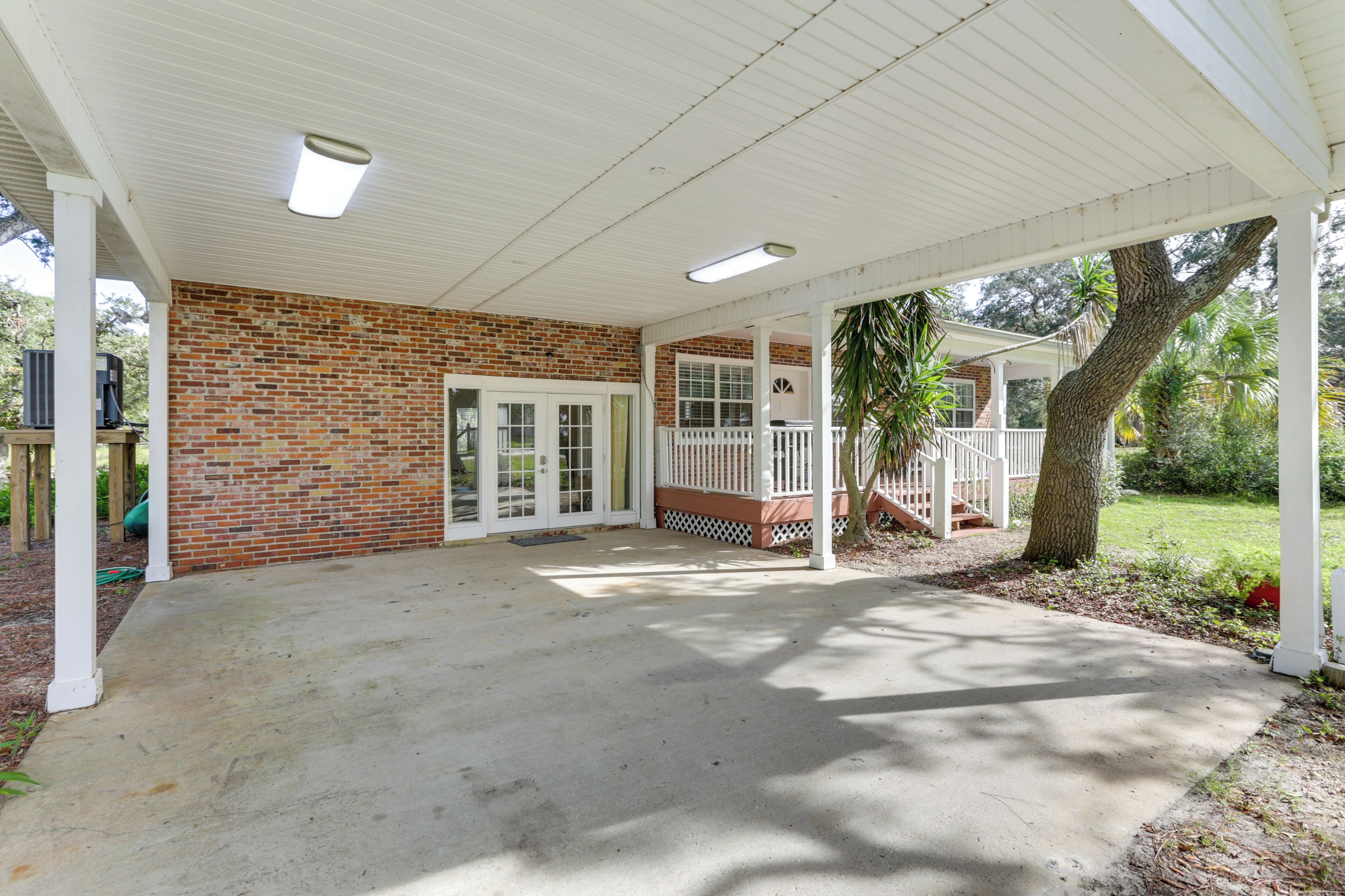 A covered patio with a brick wall, white railings, and a concrete floor.
