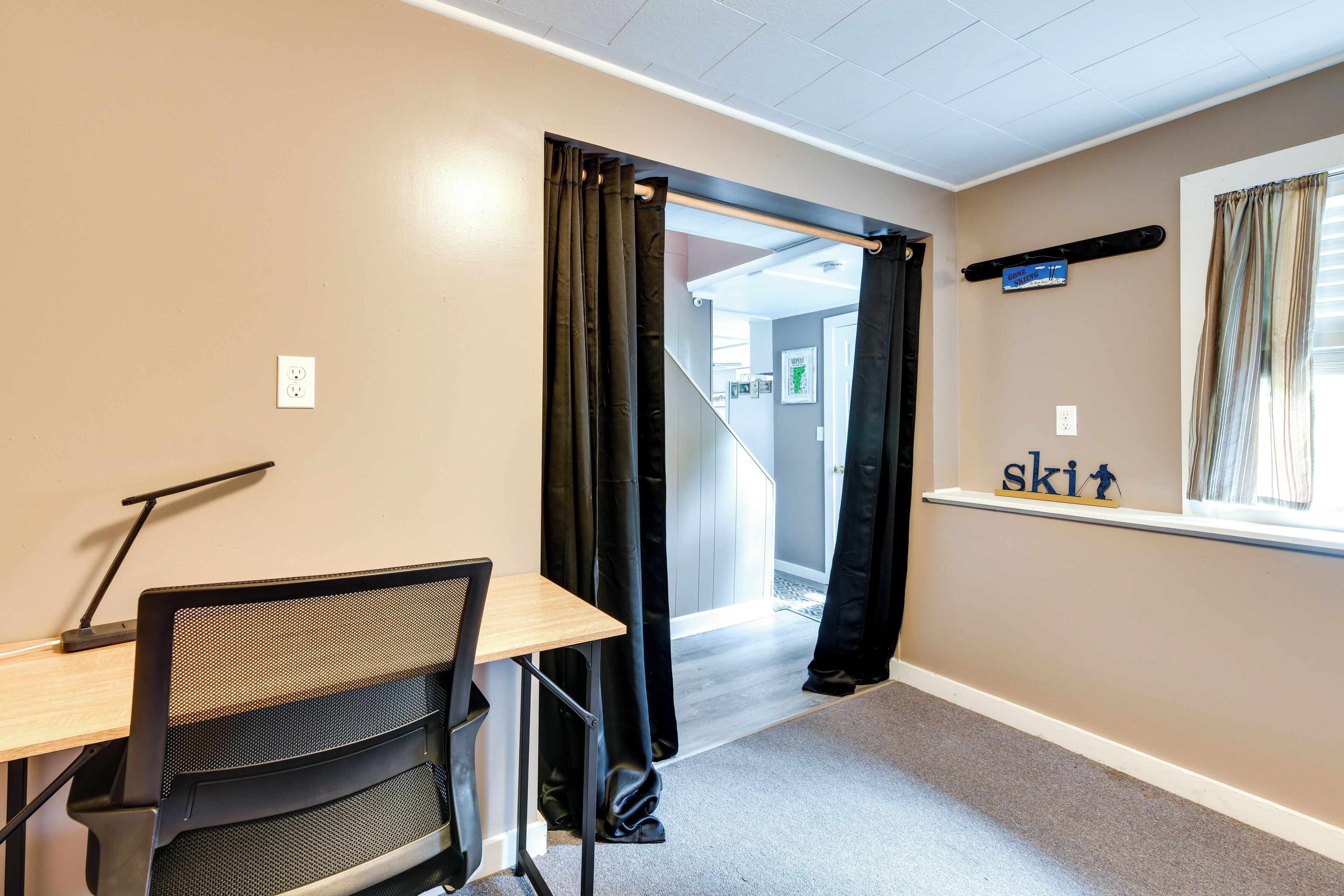 Een hotelkamer met een bureau, stoel en een raam met gordijnen.