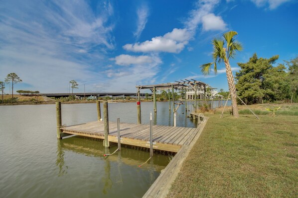 A wooden dock extending into a calm body of water, with a covered seating area and a palm tree nearby. - Waterfront Pass Christian Paradise: 1 Mi to Beach (Pass Christian)