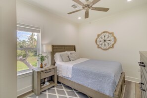 Quarto com cama, mesa de cabeceira, abajur e um objeto decorativo na parede.