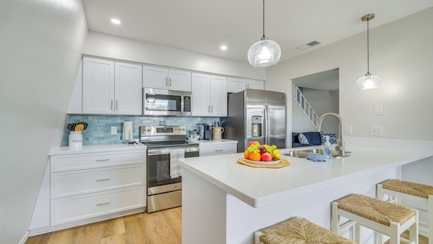 A modern kitchen with white cabinets, stainless steel appliances, and a central island with bar stools.