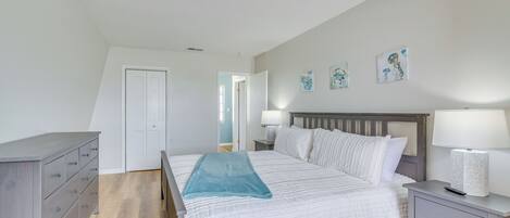 A bedroom with a bed, nightstand, dresser, and artwork on the wall.