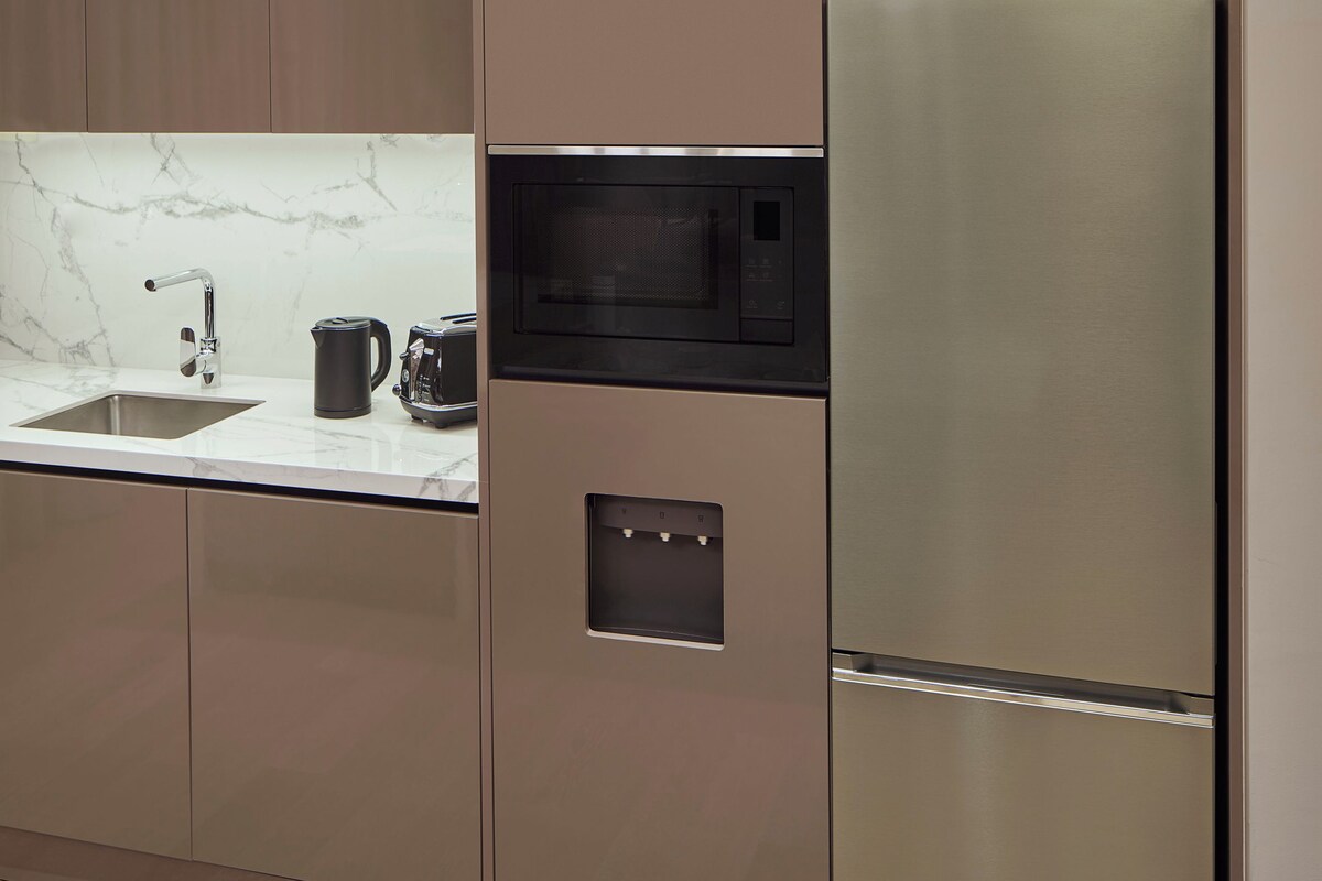Una cocina moderna con electrodomésticos integrados, encimera de mármol y suelo de madera.