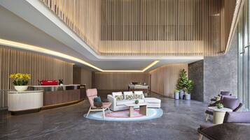 Een moderne lobby met een receptiebalie, zithoek en een wand van verticaal hout.