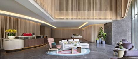 Eine moderne Lobby mit einer Rezeption, einer Sitzecke und einer Wand aus vertikalen Holzelementen.