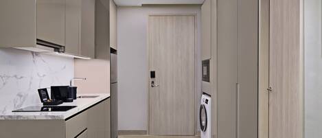 Una cocina moderna con microondas integrado, lavadora y puerta con manija.