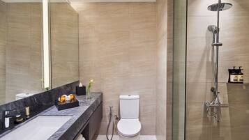 A modern bathroom with a marble sink, a toilet, and a glass-enclosed shower.