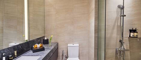 Un baño moderno con lavamanos de mármol, inodoro y cabina de ducha con paredes de vidrio.