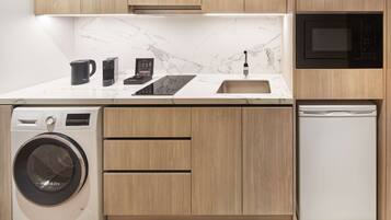 A modern kitchen with a built-in washer, dishwasher, microwave, and a marble backsplash.