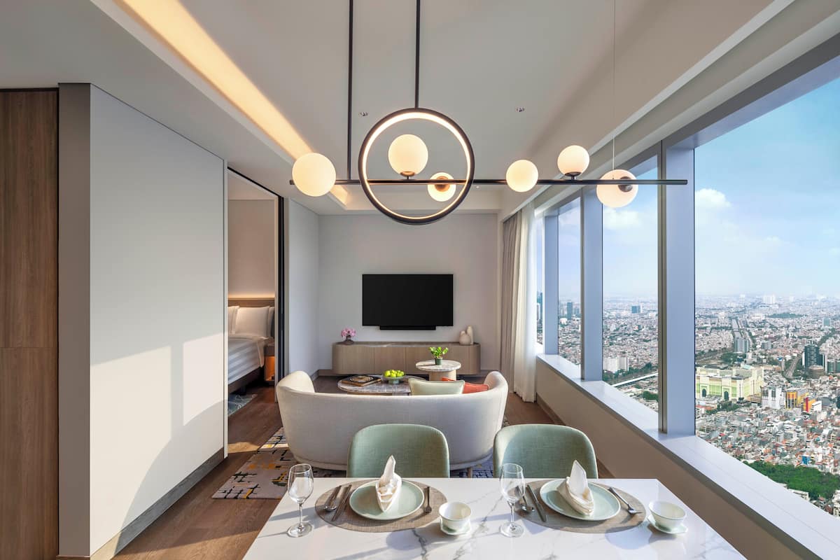 Habitación de hotel moderna con comedor, televisor de pantalla plana y vistas a la ciudad.
