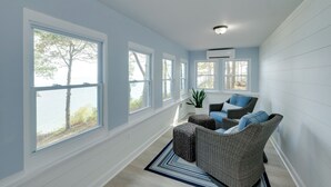 A room with large windows, wicker furniture, and a view of the outdoors. - Waterfront Views: Peaceful Chesapeake Bay Escape (Lusby)