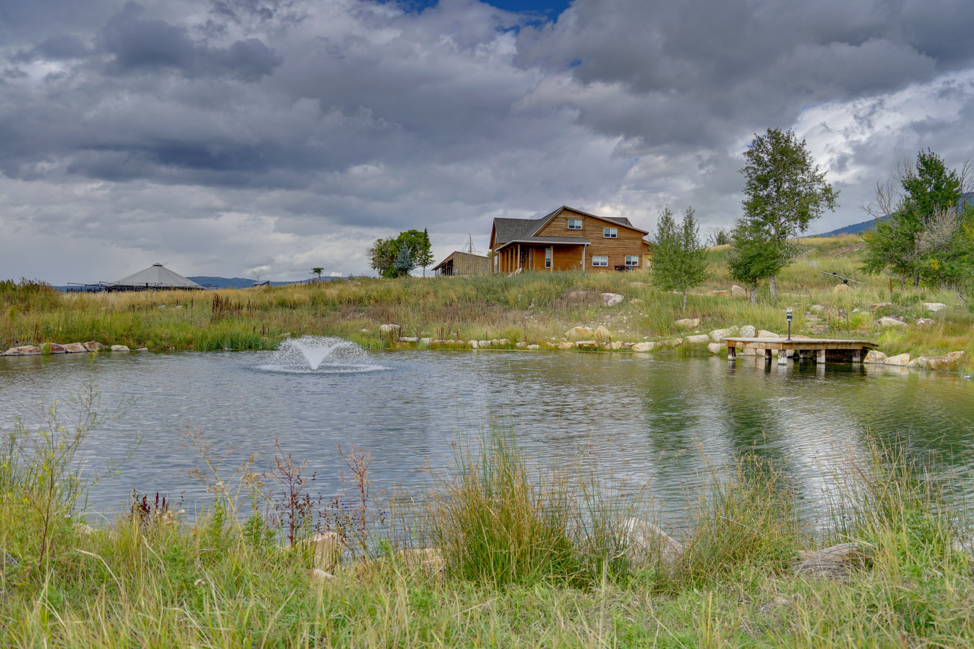 A house with a pond and a wooden dock.