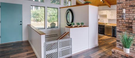 A modern kitchen with wooden flooring, a built-in stove, and a brick accent wall.