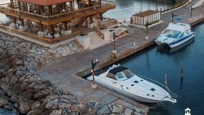 A waterfront property with a wooden structure featuring balconies, a dock with a boat, and a marina. - Welcome to Nano’s Home  (La romana)