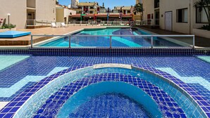 Piscina com deck revestido e vista para edifícios ao fundo.