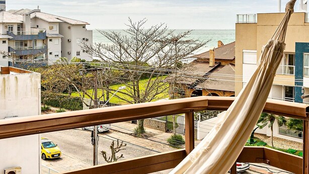 Uma rede em uma varanda com vista para o mar e edifícios.