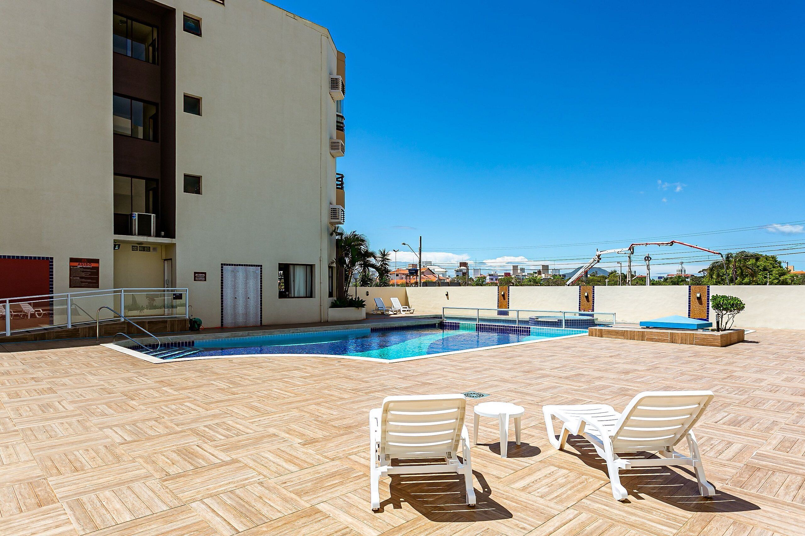 A rooftop pool area with a clear blue sky, a swimming pool, and two lounge chairs.