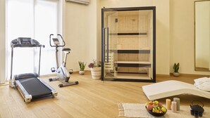 A room with a treadmill, exercise bike, sauna, and a bed with a small table and fruit bowl. - Milan Retreats Porta Romana (Milan)