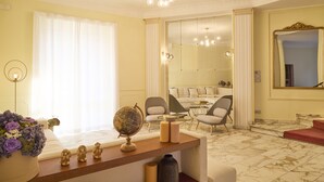 A well-lit living room with a sofa, armchairs, a coffee table, and a decorative globe on a wooden console. - Milan Retreats Porta Romana (Milan)