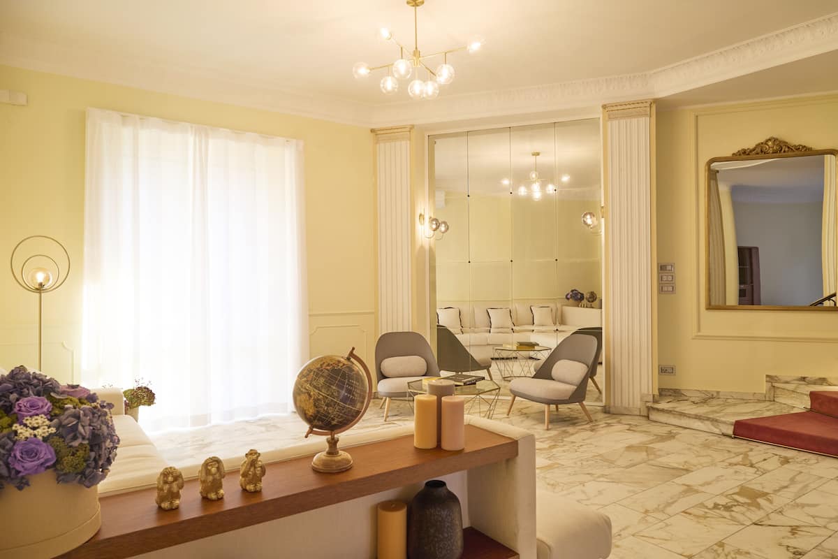 Een goed verlichte woonkamer met een bank, fauteuils, een salontafel en een decoratieve wereldbol op een houten console.