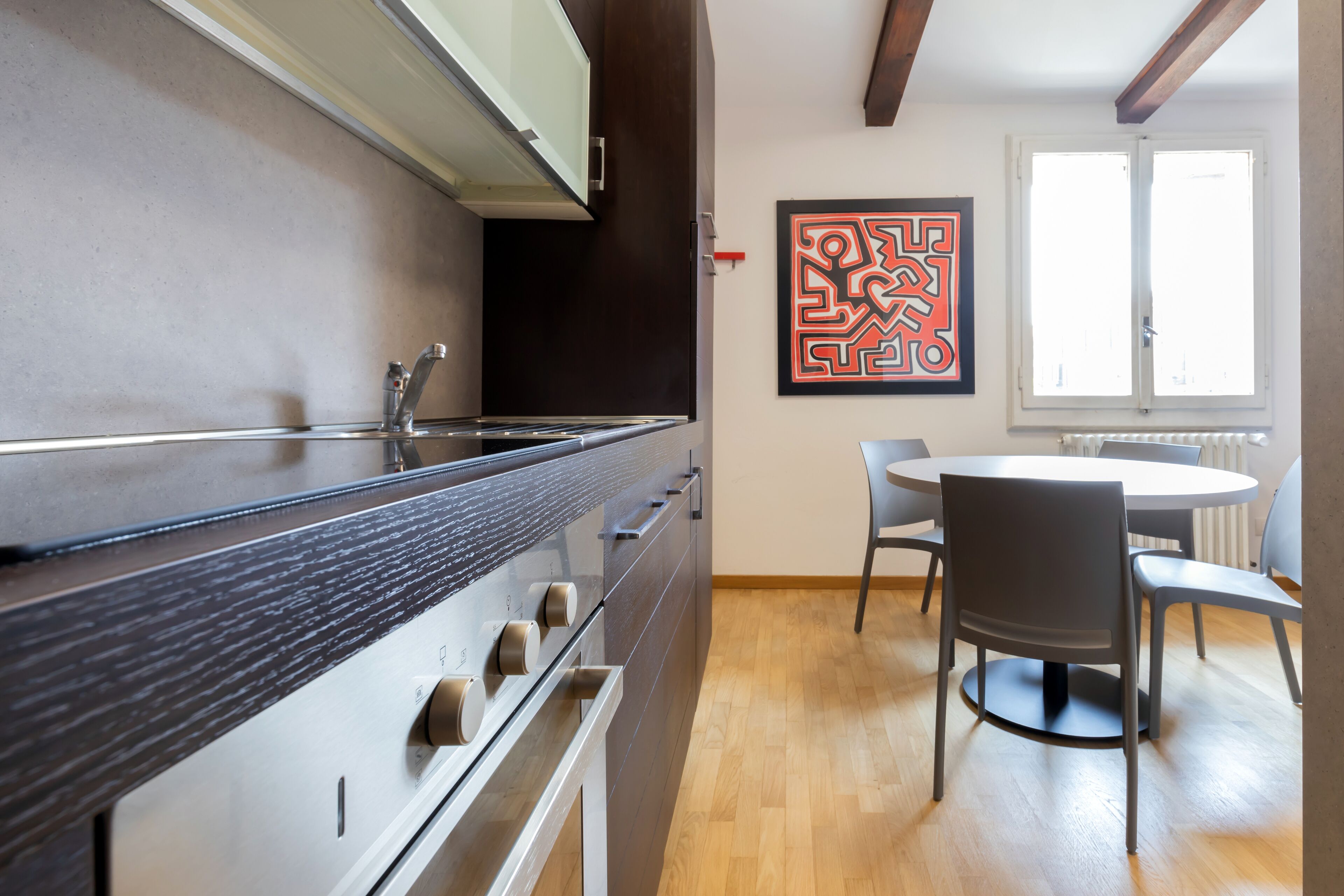 Une cuisine moderne dotée d’un four encastré et d’un coin repas avec une table ronde et des chaises.
