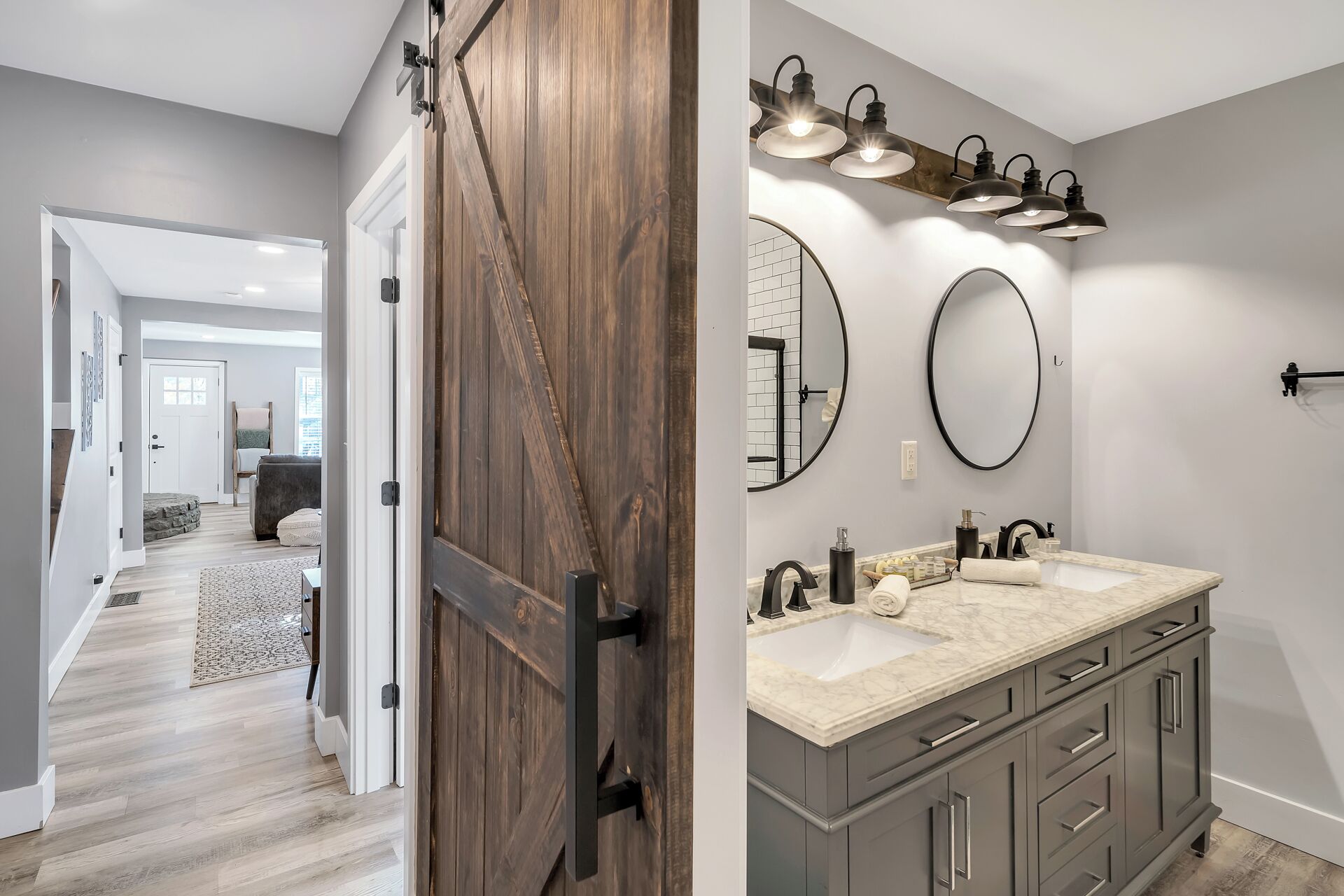 A modern bathroom with a large vanity, two mirrors, and a light fixture above the sink.