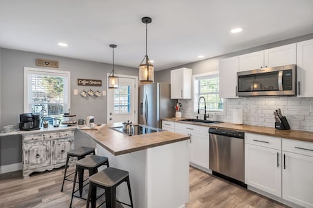 A modern kitchen with a central island, bar stools, stainless steel appliances, and a breakfast bar.