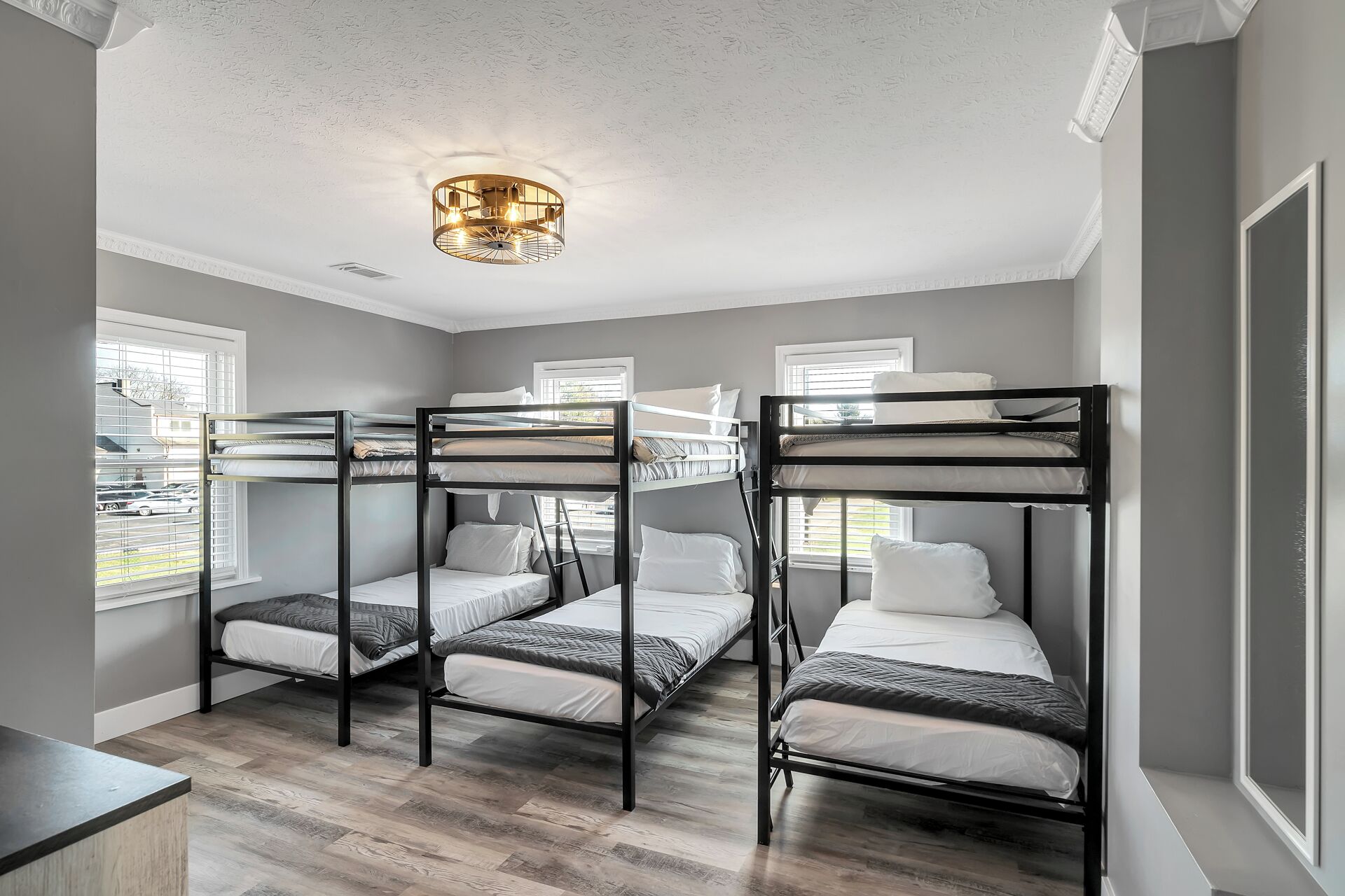 Une chambre de dortoir avec des lits superposés, un plancher en bois et un luminaire au plafond.