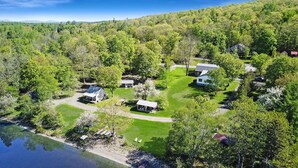 A lakeside property with multiple cabins, a covered patio, and a grassy lawn. - Portage Lakeside Cabins (Portage Lake)