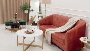 Una sala moderna con un sofá rojo, una mesa de centro redonda y un ventilador de techo.