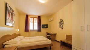 Ein Hotelzimmer mit Bett, Schreibtisch, Fernseher und Kleiderschrank.