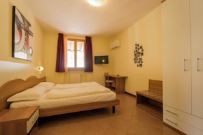 Una camera d'albergo con un letto, una scrivania, una televisione e un armadio.