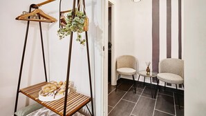 Ein Zimmer mit einer hängenden Holzstange, zwei Stühlen, einem kleinen Tisch und einer hängenden Pflanze.