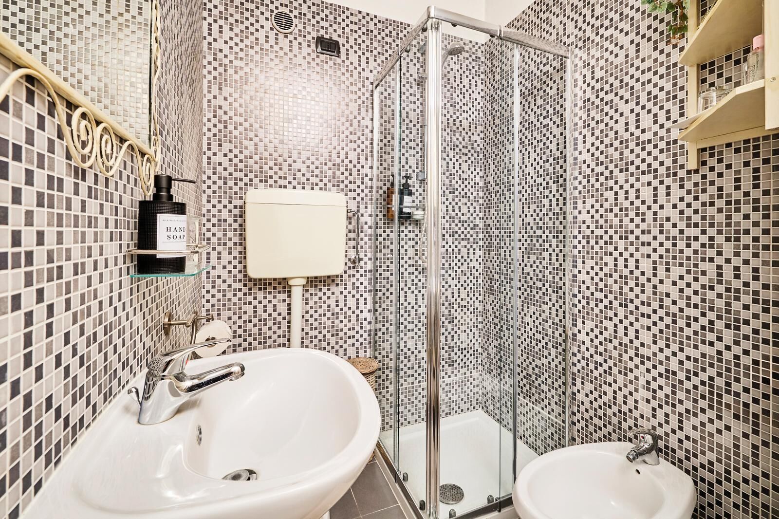 A bathroom with a shower, two sinks, and a toilet.