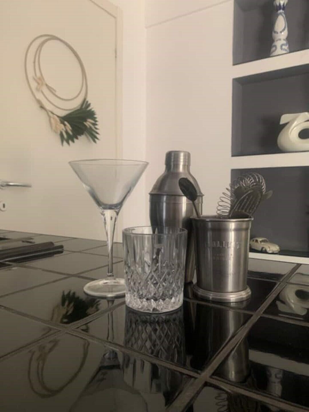 Een keukenblad met een martini glas, een cocktailshaker en een metalen bak met een garde.