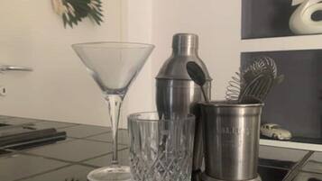 Een keukenblad met een martini glas, een cocktailshaker en een metalen bak met een garde.