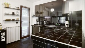 Eine moderne Küche mit schwarzen Fliesenarbeitsplatten, einem eingebauten Herd und einem großen Fenster mit Jalousien.