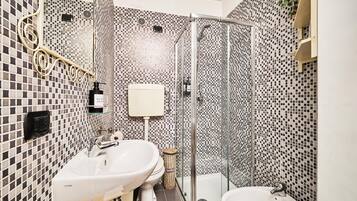 A bathroom with a shower, two sinks, and a toilet.